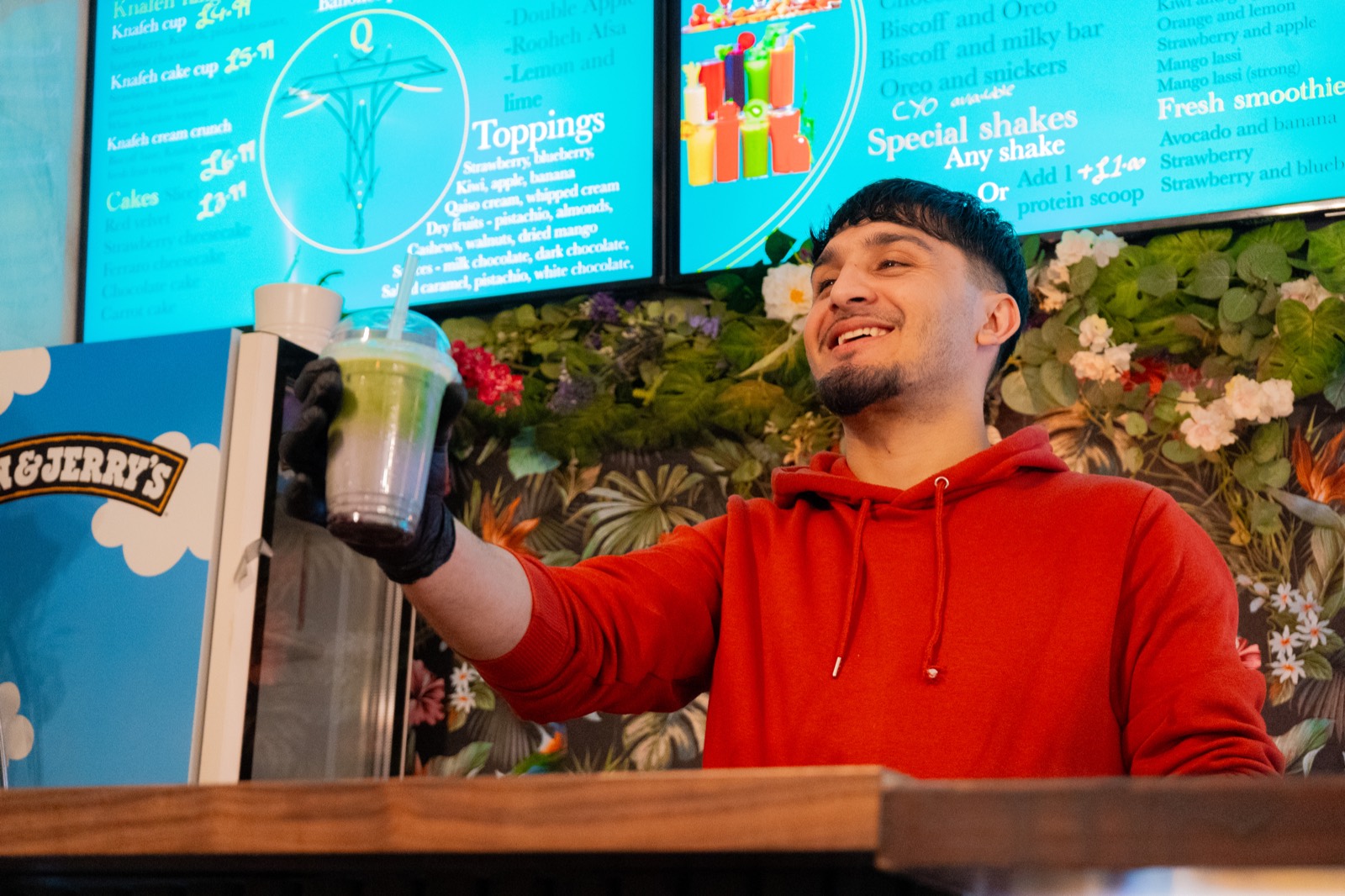 A member of the Qaiso team handing over a matcha shake at the counter