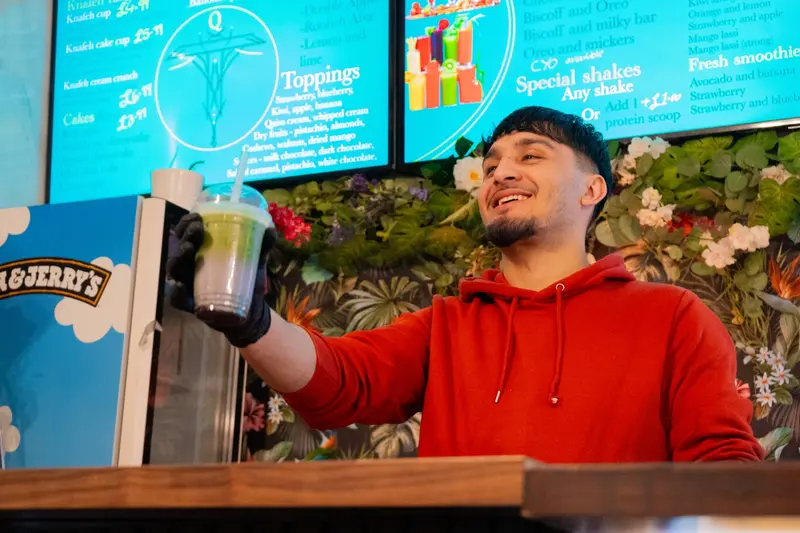 A member of the Qaiso team handing over a matcha shake at the counter